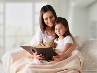 Mother and daughter readin book in bed