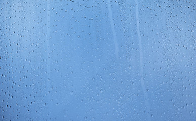 From below abstract raindrops on glass on background of cloudy sky. Rain drops on window glasses surface with cloudy background . Natural Pattern of raindrops isolated on cloudy background.