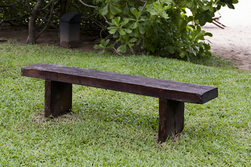 Old wooden bench in the middle of the lawn surrounded by the beach.