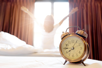 Morning of a new day, alarm clock wake up man sitting in the room. A man stretch the muscles at...
