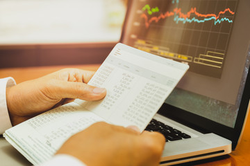 Naklejka premium Businessman hands holding saving account passbook with stock money cahrt.