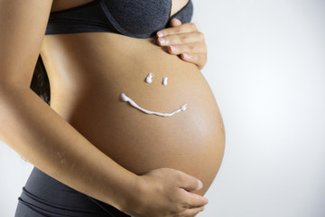 Belly of pregnant woman and smile from moisturizing cream.