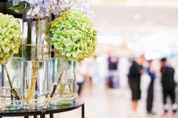 soft focus of green hydrangea flower in glass with blur people in convention hall
