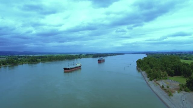 Drone aerial flyby of 2 cargo ships on the river waiting to load cargo