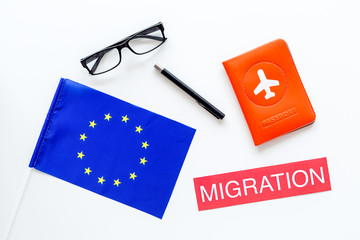 Schengen visa. Immigration to Europe concept. Text immigration near passport cover and european flag on white background top view
