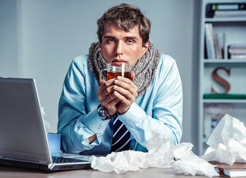 Bad feeling. Sick worker has high temperature. Photo of young man in office suffering virus of flu. Medical concept.