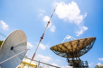 Signal Tower and satellite dish The sky is big and the clouds are white as the backdrop.