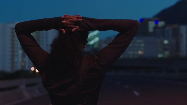 young woman runner athlete resting after running exercise workout in urban city at night background