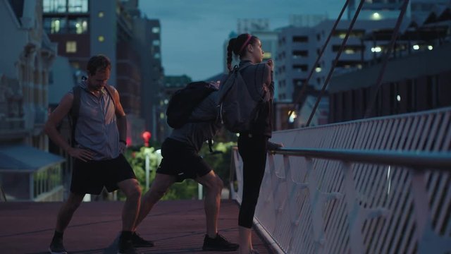 group of diverse runners stretching athletes warm up preparing running exercise challenge together in urban city evening at night