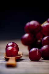 Grapes on a wooden spoon on a black background still life.