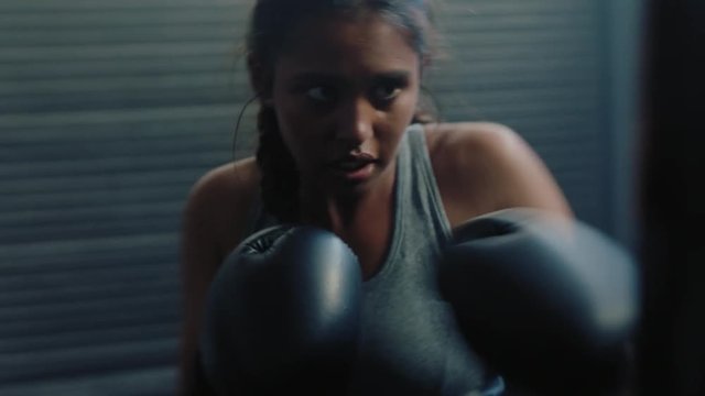 hispanic woman athlete training kickboxing exercise workout punching bag tough female fighter practice boxing in gym enjoying fitness lifestyle
