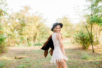 Beautiful young girl with blond hair in a suede jacket with fringed and black felt hat in the...