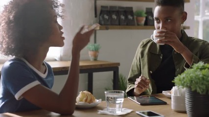 young black women friends in cafe talking drinking coffee enjoying conversation socializing together sharing friendship connection in restaurant shop