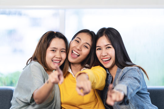 Young attractive asian women or three best friends sitting and pointing you looking at camera with positive fun attitude. Group of asia student female people smile and laugh happy together concept.