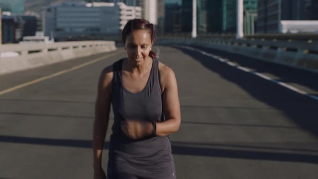 mature indian woman athlete running in city enjoying healthy fitness lifestyle senior athletic female resting after intense morning run workout jogging on urban road 