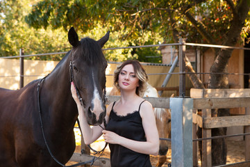 Young beautiful woman next to a horse in a stable