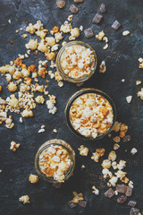Caramel sweet popcorn in glass jars on dark background, top view