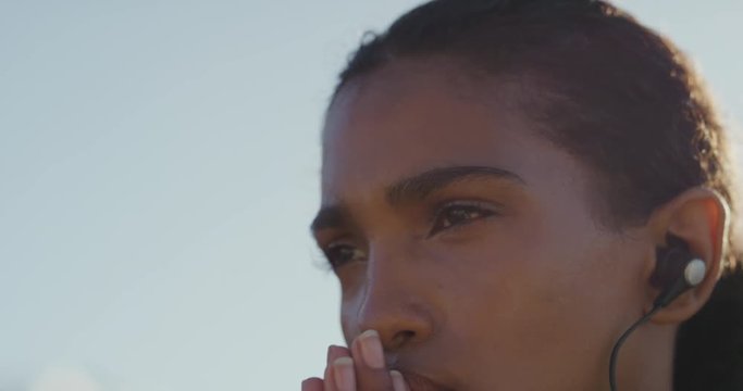 portrait young hispanic woman runner preparing for intense running exercise female athlete training in urban city at sunrise wearing earphones listening to motivation music close up