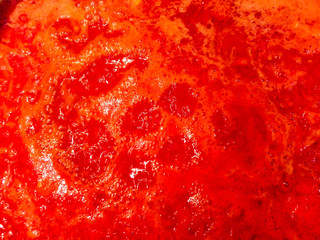 Closeup of boiling tomato sauce in a saucepan on the stove.
