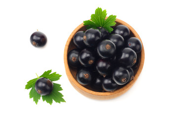 black currant in wooden bowl with green leaf isolated on white background. top view
