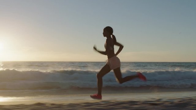 young african american woman running on beach sprinting exercising intense cardio workout competitive black female training early morning seaside sunrise 