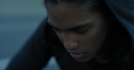 young hispanic woman runner resting exhausted after intense running exercise in city at sunrise training cardio female athlete wearing earphones close up