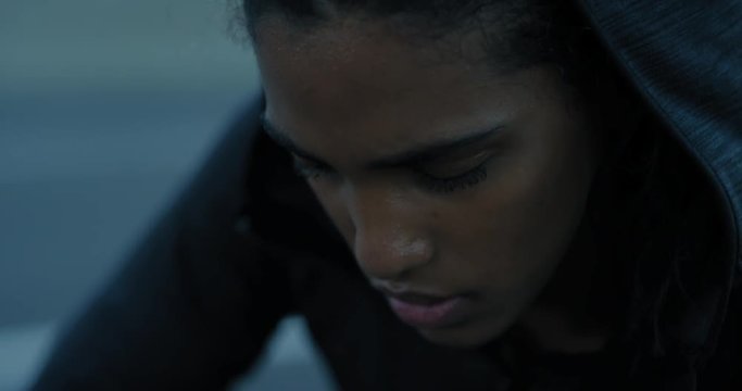 young hispanic woman runner resting exhausted after intense running exercise in city at sunrise training cardio female athlete wearing earphones close up