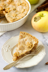 A traditional American apple pie decorated with stars and sugar, apples and cinnamon on a light background.