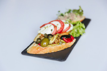 sandwiches of white bread, ham, tomato, cucumber, meat, olives, greens, lettuce, cheese on a plate