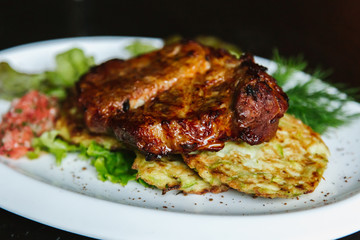 Pork steak with mushrooms, tomatoes, cucumbers, pepper, sauce on a black background