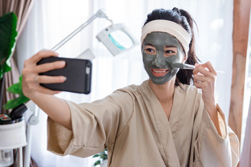 Fototapeta na wymiar Young woman selfie when using facial mask mud 