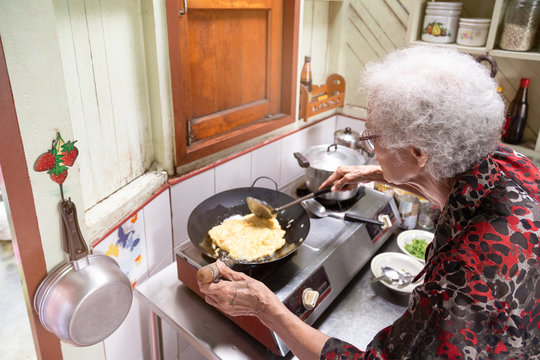 Senior Asian Woman Cooking Omelet In Kitchen At Home,lifestyle Of Asian Old Woman Concept