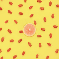 Nuts almonds on a yellow background with a cut orange, texture, pattern, top view, close-up....