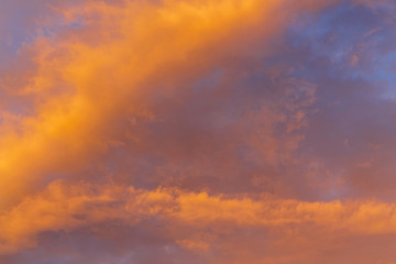 Naklejka na ściany i meble Abstract background with a texture of clouds at sunset similar to a fire. Heavenly landscape. A beautiful morning blue sky painted in the sun in bright red and orange colors