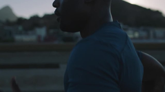 muscular african american man running in city road jogging athletic male exercising endurance workout in urban street at sunrise close up