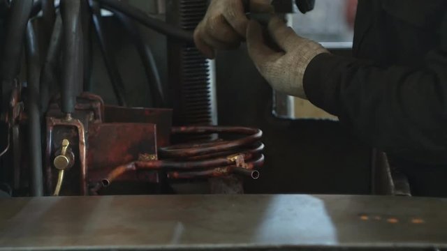 The working specialist prepares equipment for hardening and heat treatment of metal parts by heating, close-up, industry, hardening