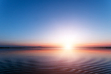 Beautiful, red dawn on the lake. The rays of the sun through the fog. The blue sky over the lake,...