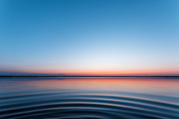 Obraz premium ircles on the water against a beautiful, pink sunset. The magic time of day.