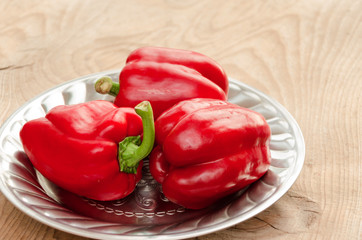 Red paprika in rustic metal plate. Red bell pepper. Wooden background.
