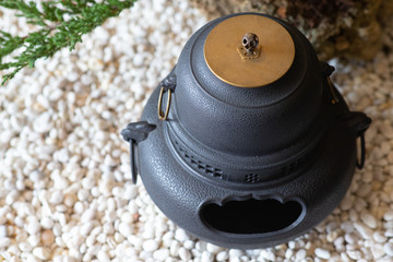 Obraz na płótnie Canvas black Pot for fragrant candles on white gravel.