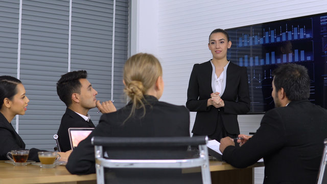 Business girl explaining graph on Monitor screen to the Colleagues in meeting room. 