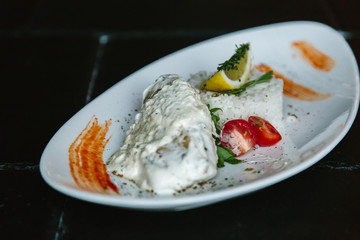 Rice and fish dish with a white sauce, lemon and greens