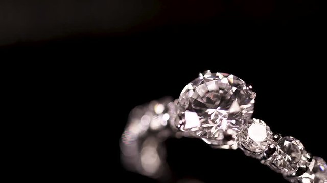 Engagement diamond ring rotating on black background, macro with shallow DoF