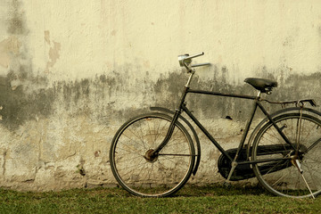 Fototapeta na wymiar Retro Rusty Black Bicycle against Old Damaged Plaster Wall - Vintage Effect Style Image