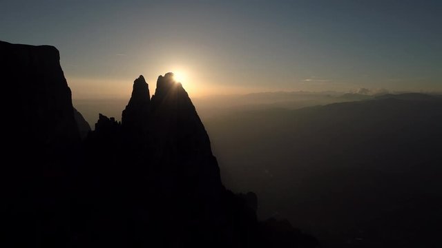 Aerial - Sun shines in the silhouette of two mighty peaks in Dolomites