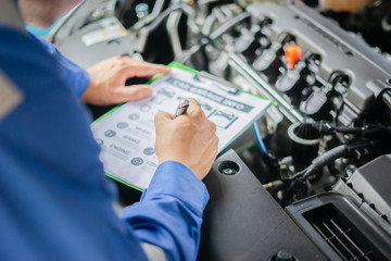 car service,repair,maintenance    - Asian auto mechanic man or Smith writing to the clipboard at...