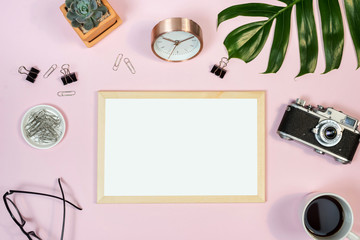 Feminine desk workspace with white board frame mockup on pink background. Flat lay, top view.