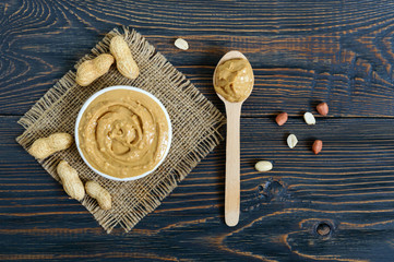 Peanut butter in a ceramic bowl on a wooden table. A traditional product of American cuisine. Top...