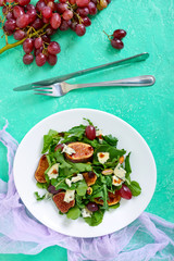 Classic salad with figs, arugula, blue cheese, grapes on a white plate. Tasty vegetarian dish. The top view