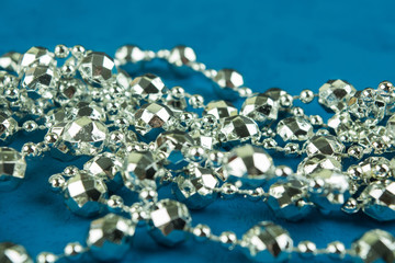 A silver christmas garland on blue background with selective focus
